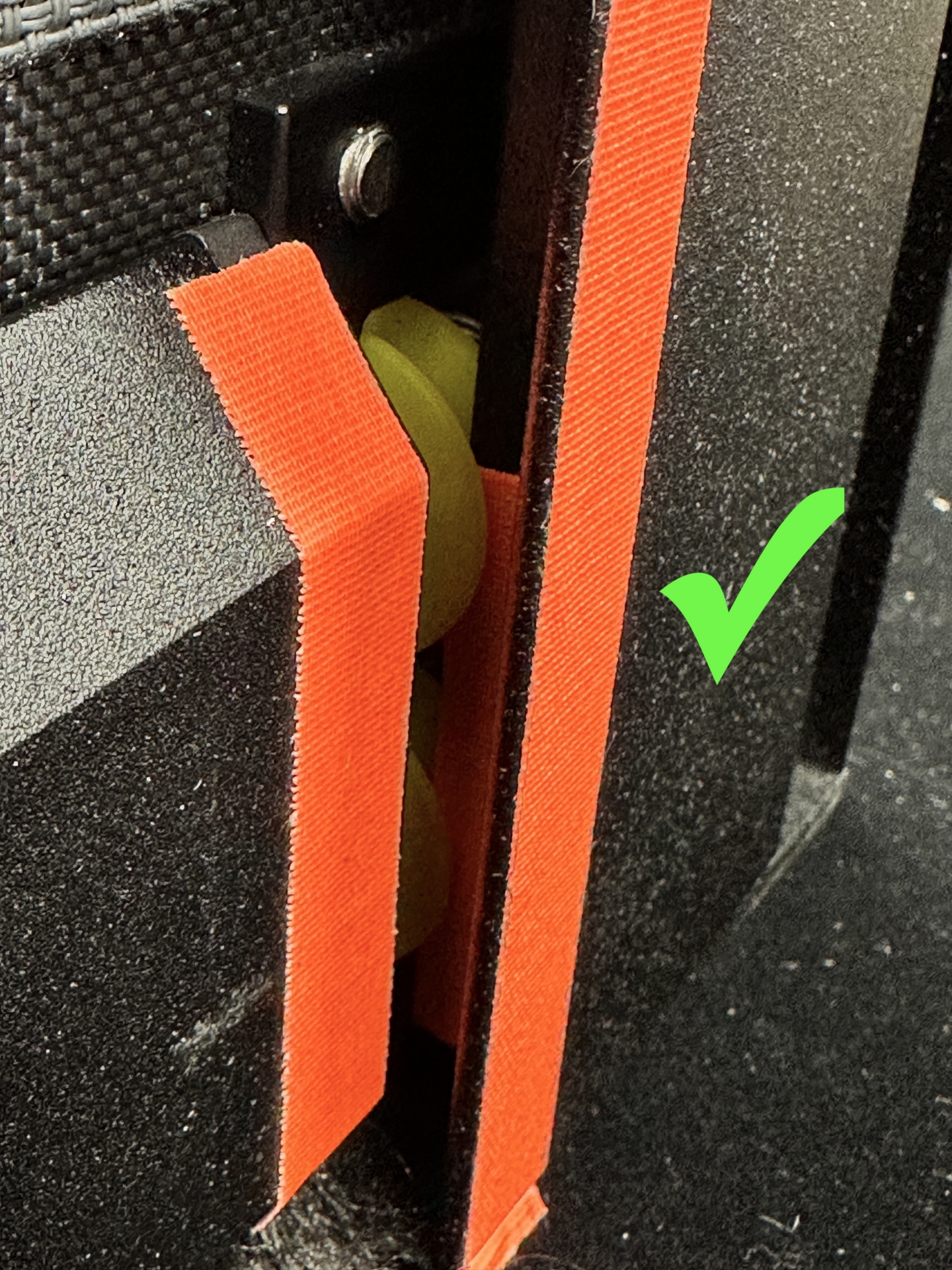 Orange strap routed correctly through KAOS motor housing gap, green checkmark indicating proper installation
