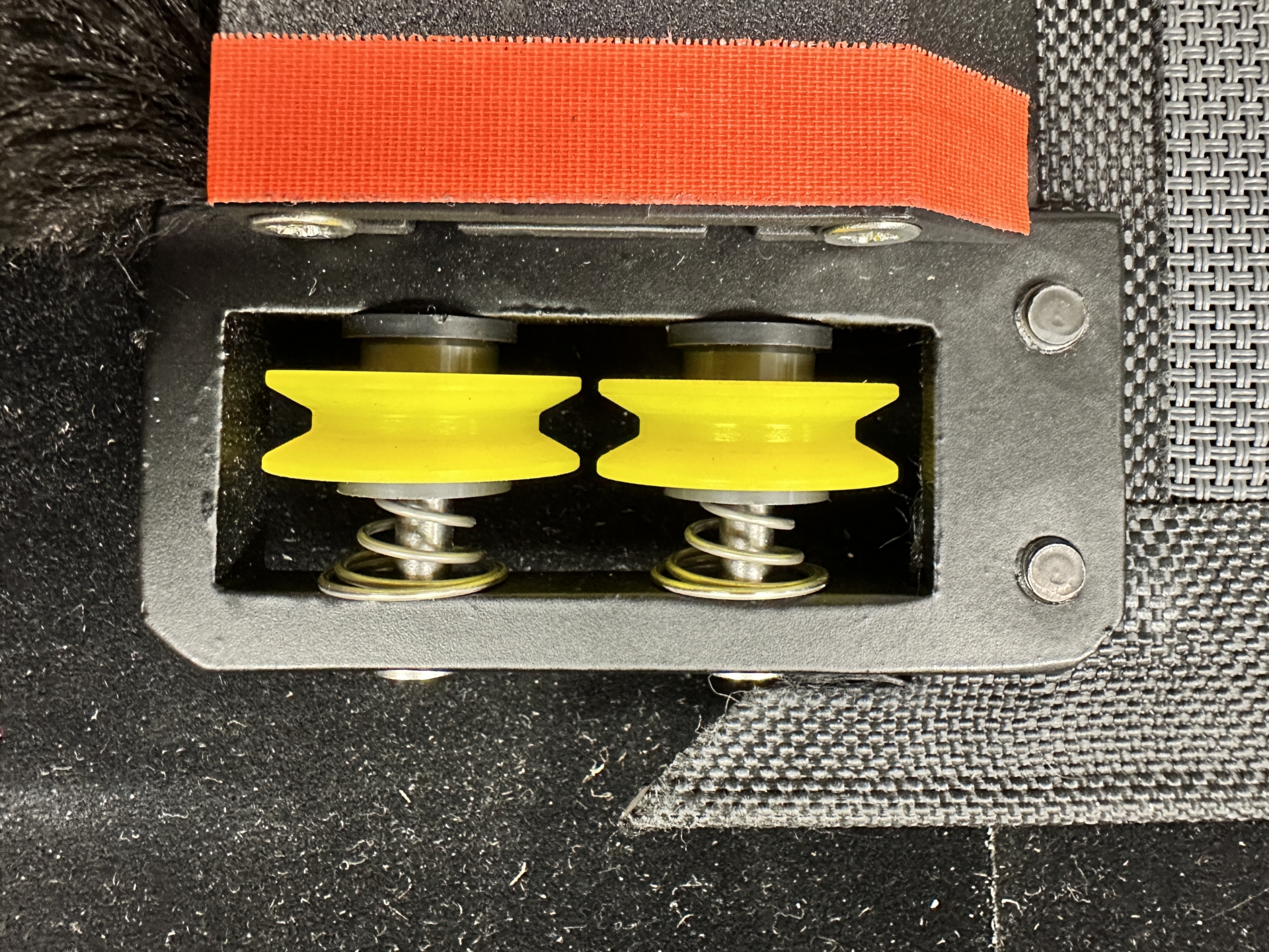 Two yellow spring-loaded roller wheels inside open KAOS motor carriage housing