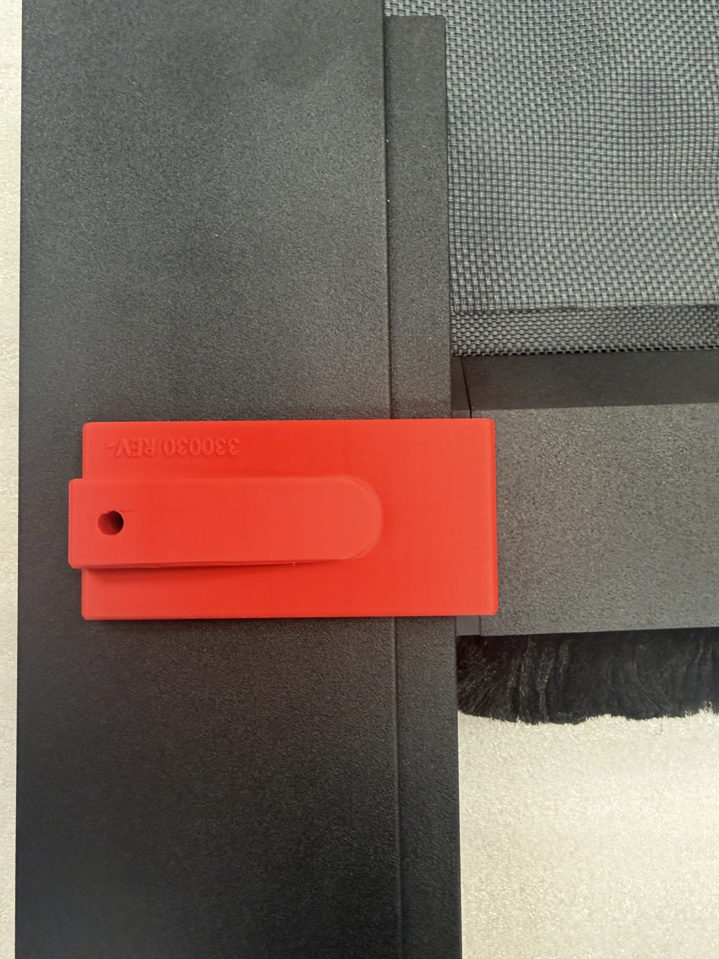 Red shipping restraint clip labeled 330030 REV- attached to KAOS track frame corner during transport