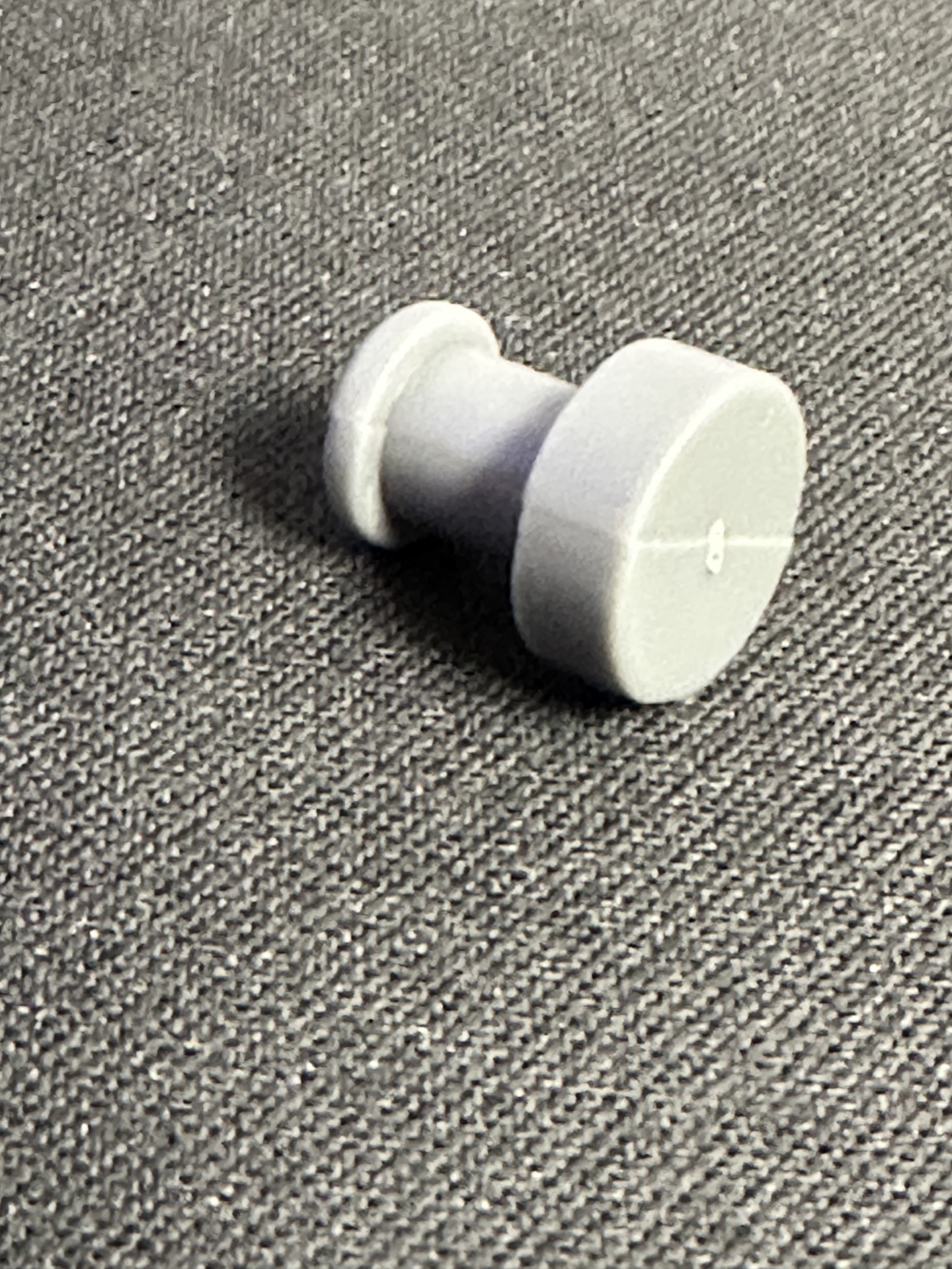 White plastic spool-shaped post with flanged ends for inserting into frame channel