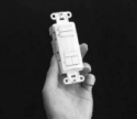 Hand holding a white DecoSet keypad with multiple white buttons on front