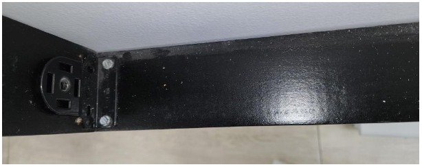 Black shade housing bracket mounted in corner of window frame, viewed from below