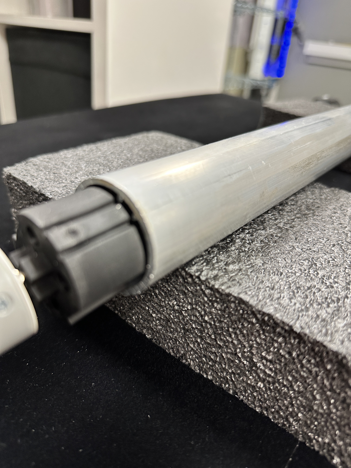 Roller tube with motor drive end and collar resting on foam padding during motor removal step