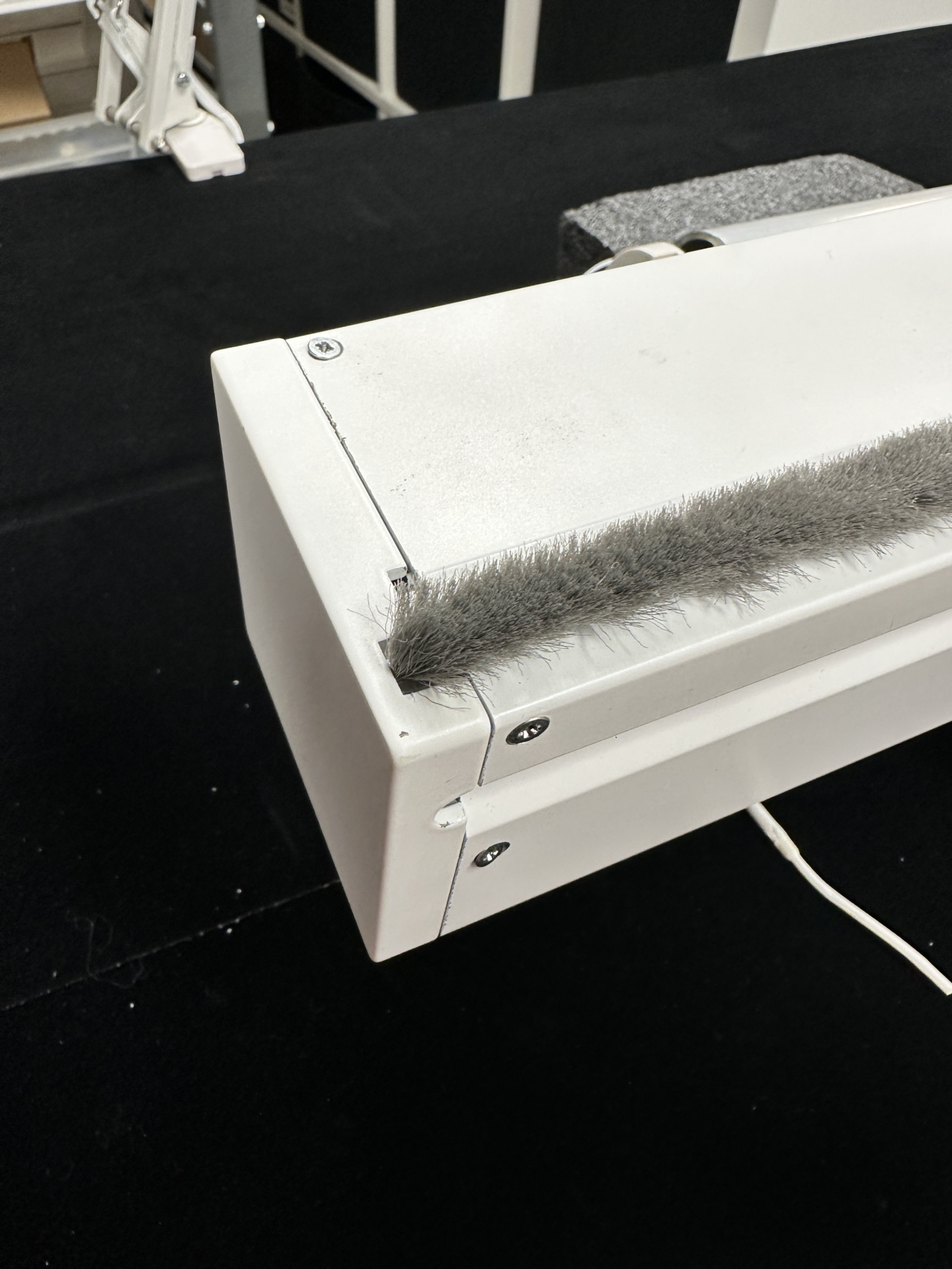 White cassette housing corner showing gray brush seal strip along the top opening edge