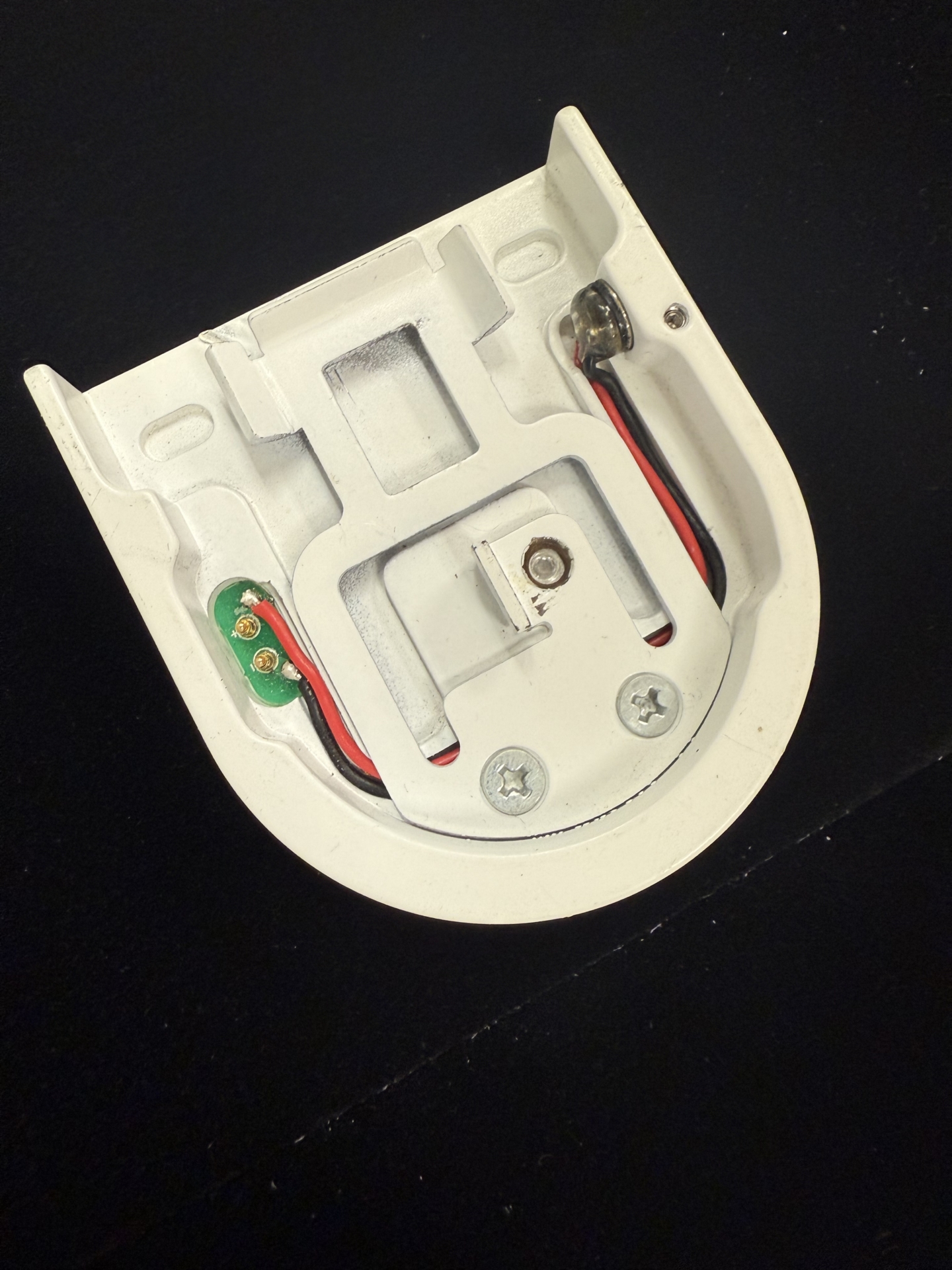 Tombstone end cap interior showing PCB board, red and black wiring, charging magnet, and two Phillips screws