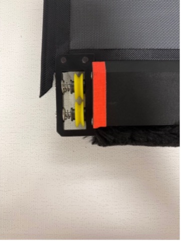 Bottom corner of weight bar end cap with yellow roller wheel and red fabric tab visible