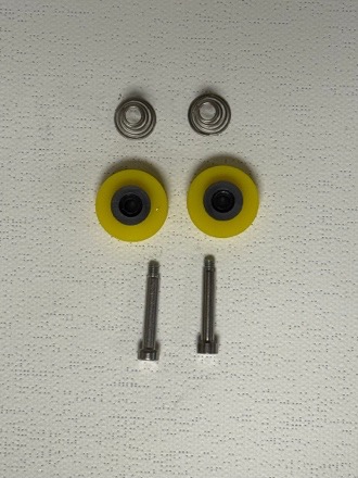 Two yellow guide wheels with bearings, two springs, and two mounting screws laid out on white surface