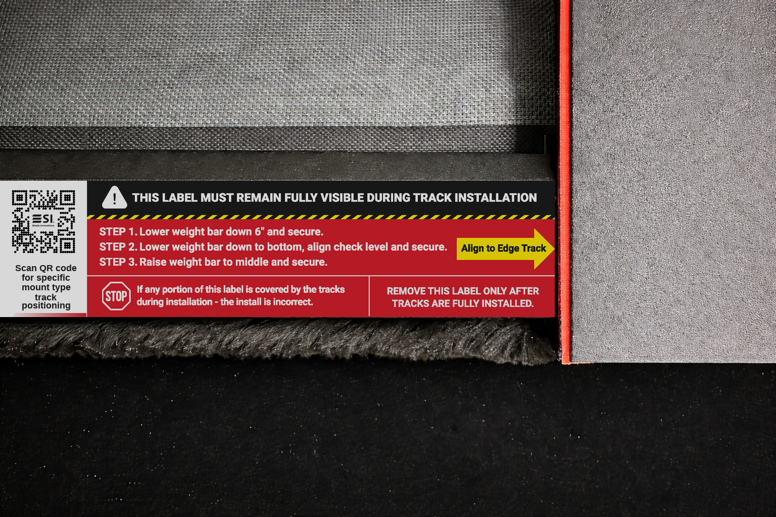 Red track installation warning label on shade showing three weight bar steps and edge track alignment arrow