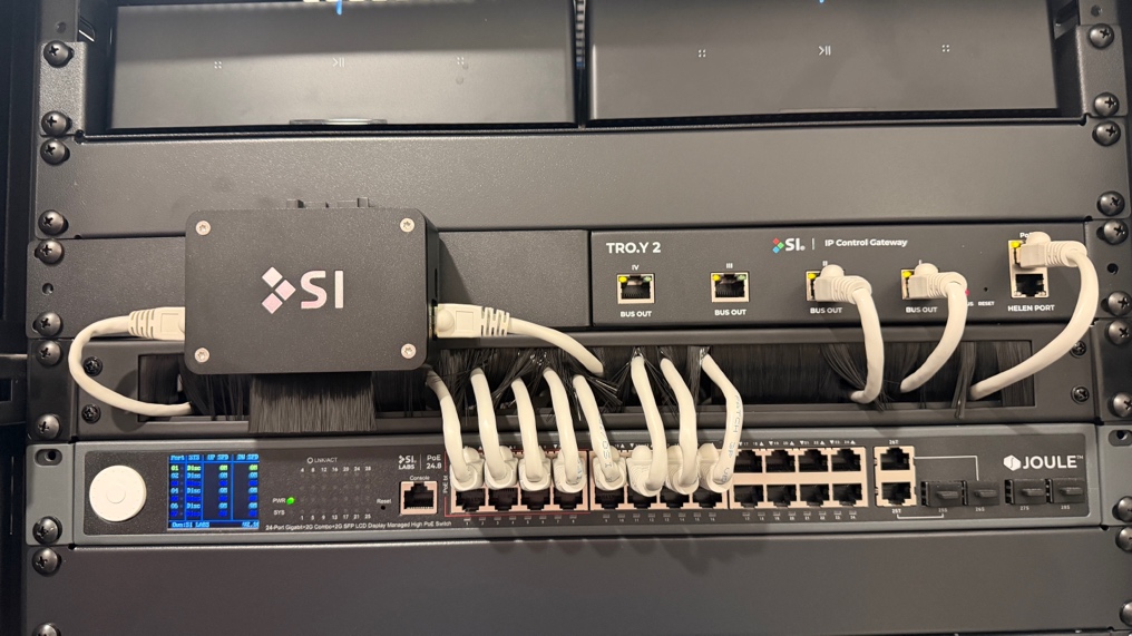 A TriMesh bridge installed in a rack alongside a TRO.Y 2 and the PoE switch that powers it.